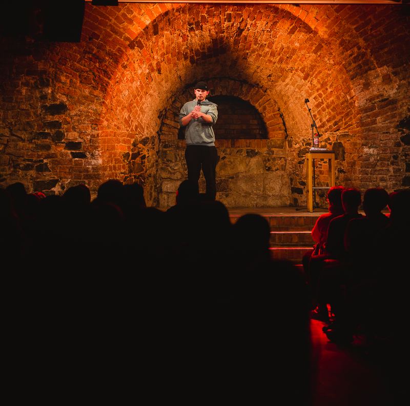 Comedian vor rot beleuchtetem Backstein-Torbogen, Moritzbastei Leipzig