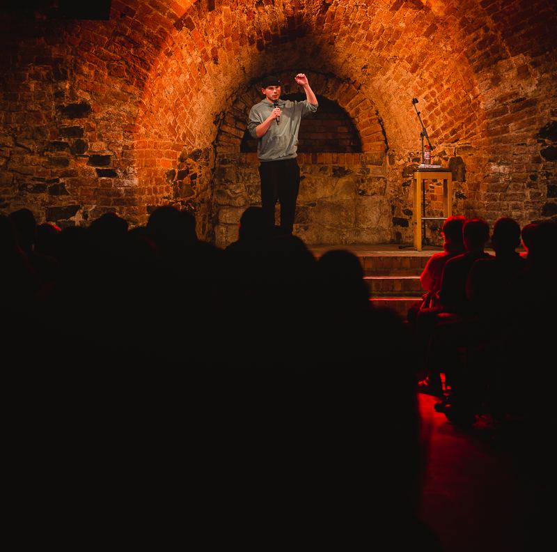 Comedian vor rot beleuchtetem Backstein-Torbogen, Moritzbastei Leipzig